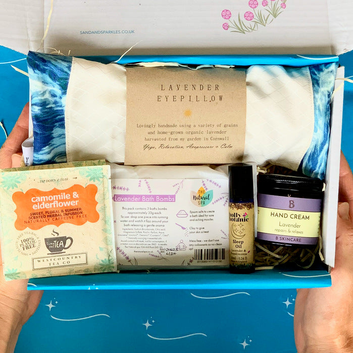 Wellbeing Gift Set with Devon and Cornish products including organic lavender eye pillow, bath bombs, hand cream, sleep oil and herbal tea in Sand and Sparkle Gift Box